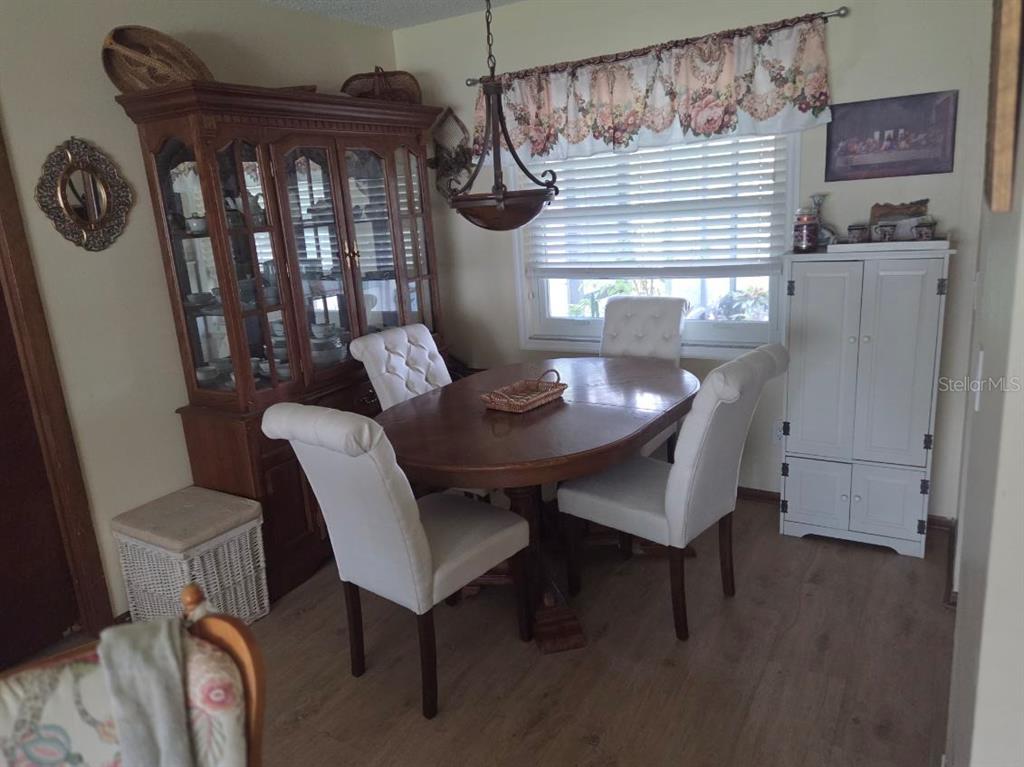 A dining room features a wooden table with four white chairs, a hutch, and blinds — 9241 TOBY LANE, ORLANDO, FL