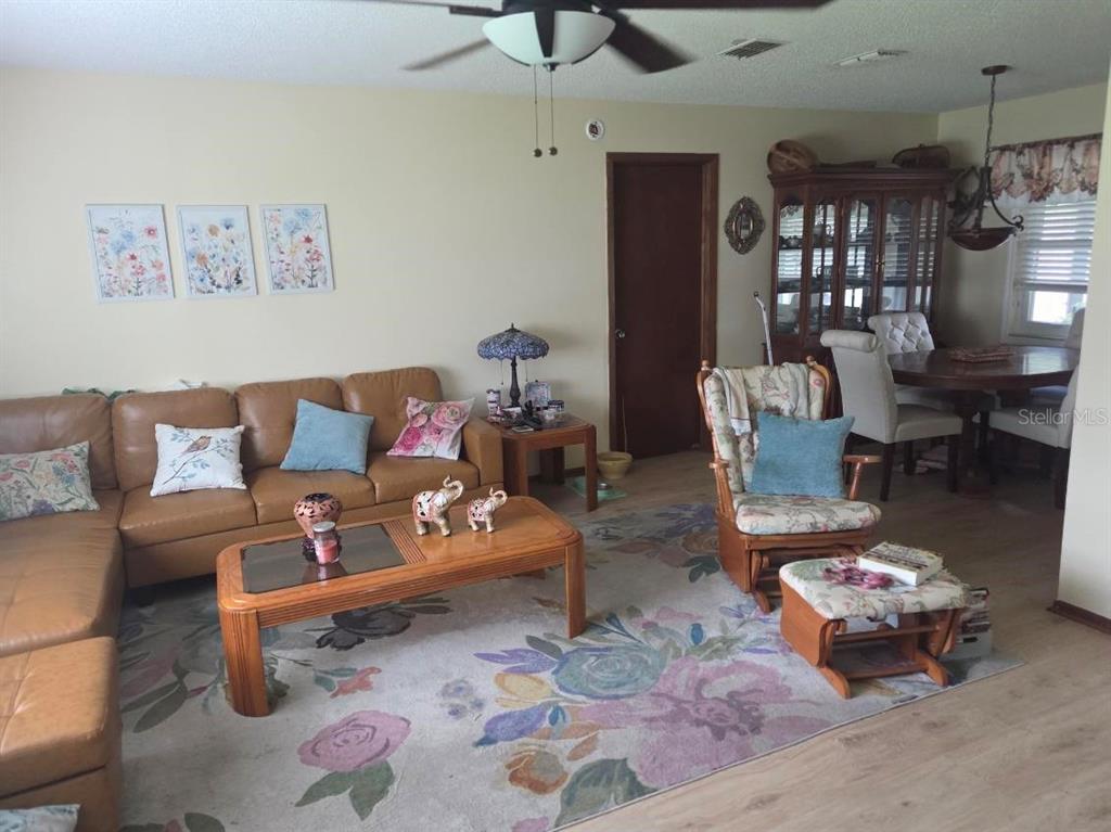 A living room features a tan leather sectional, floral area rug, and a dining area — 9241 TOBY LANE, ORLANDO, FL