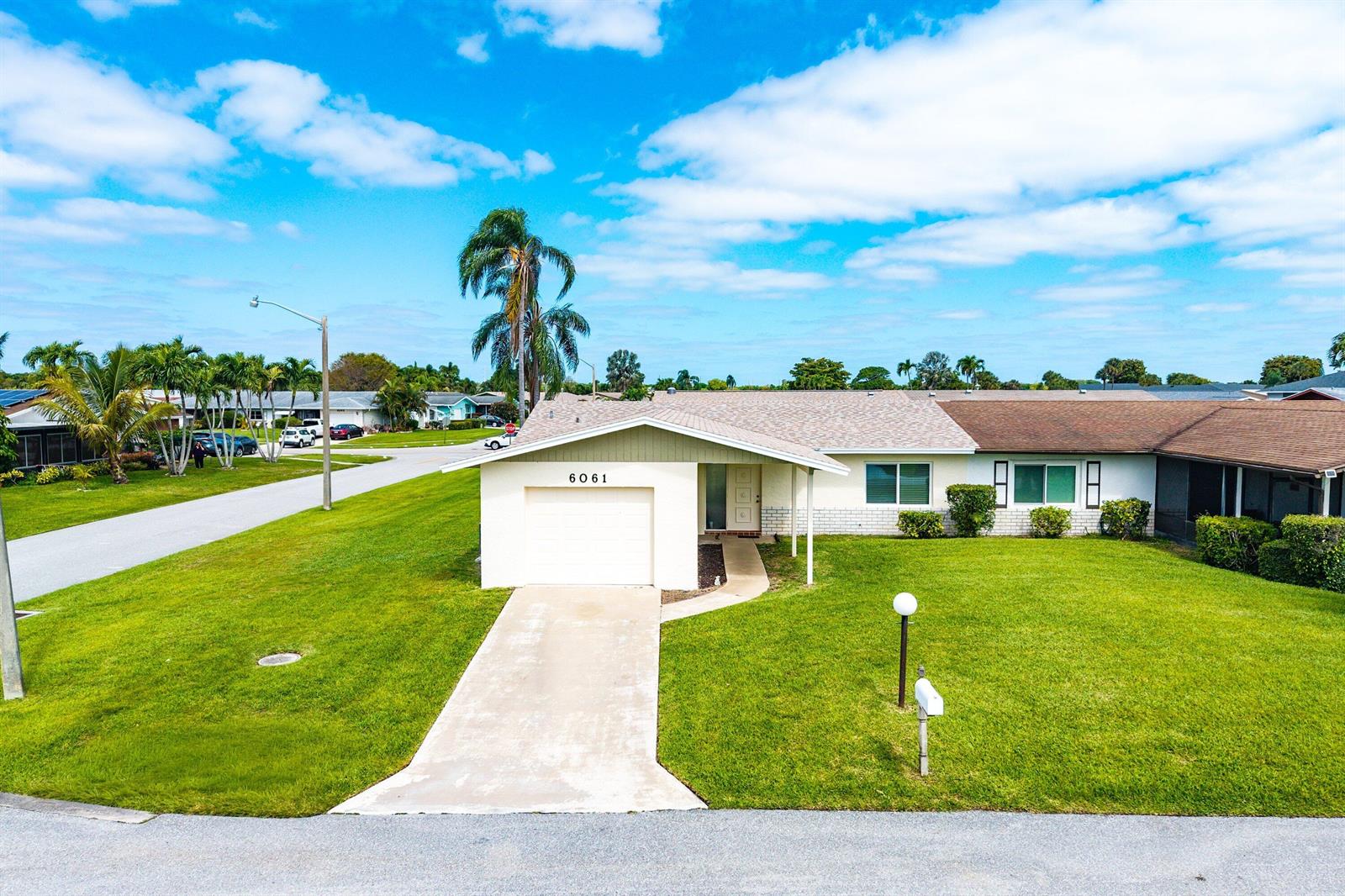 An exterior view of a single-story house with a garage, driveway, and front lawn — 6061 Stanley Lane, Delray Beach FL 33484, DELRAY BEACH, FL