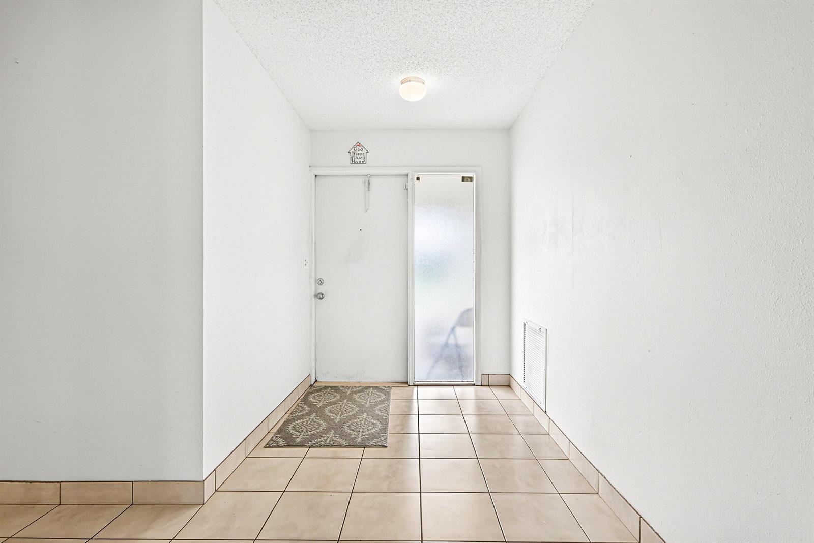An entryway features white walls, a tiled floor, a white front door, and a sidelight — 6061 Stanley Lane, Delray Beach FL 33484, DELRAY BEACH, FL