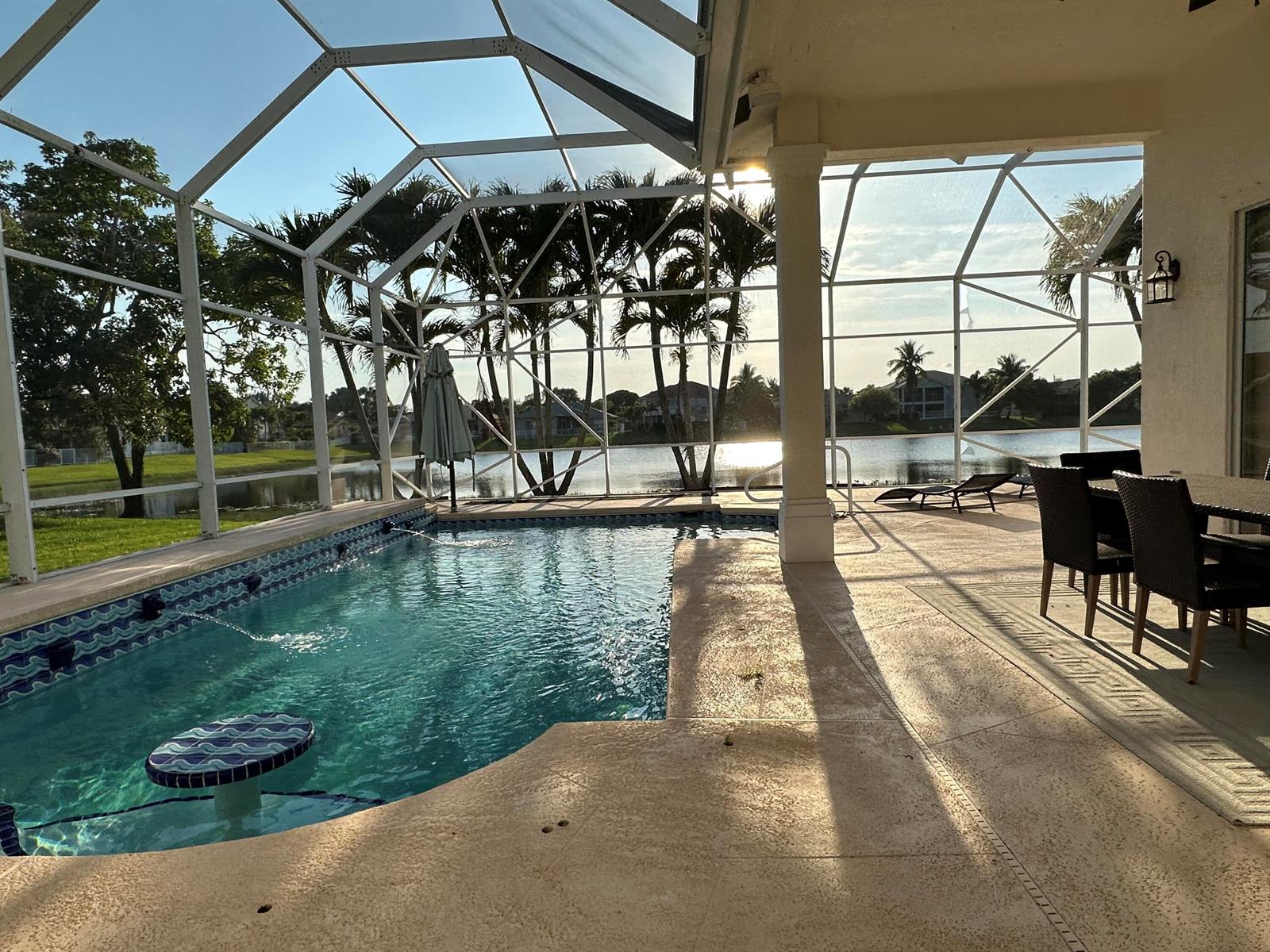 A screened-in pool patio overlooks a lake with palm trees in the background — 11750 Osprey Pointe Circle, Wellington FL 33449, WELLINGTON, FL