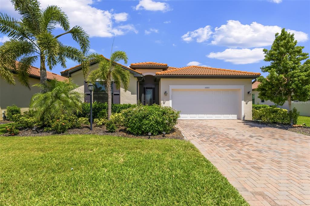 A single-story house with a tiled roof, a two-car garage, and a brick paver driveway — 10103 MARBELLA DRIVE, BRADENTON, FL