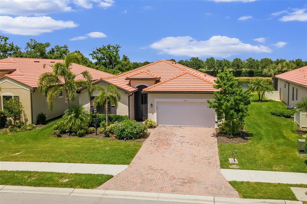 A single-story house with a tiled roof, a brick driveway, and a two-car garage — 10103 MARBELLA DRIVE, BRADENTON, FL