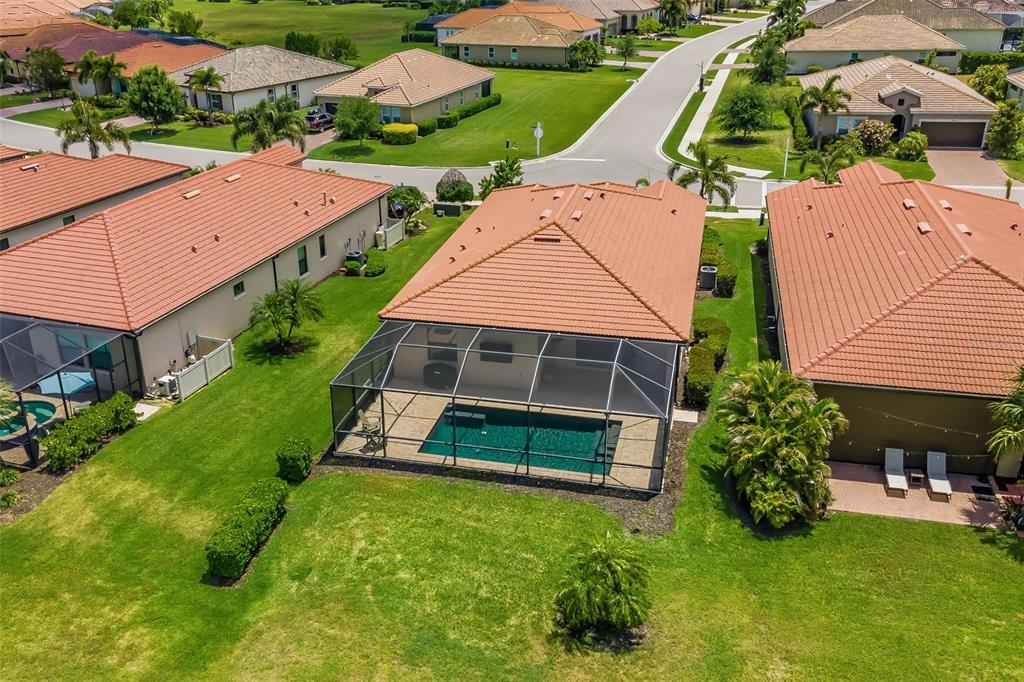 An aerial view shows a house with a tiled roof, a screened pool, and lawn — 10103 MARBELLA DRIVE, BRADENTON, FL