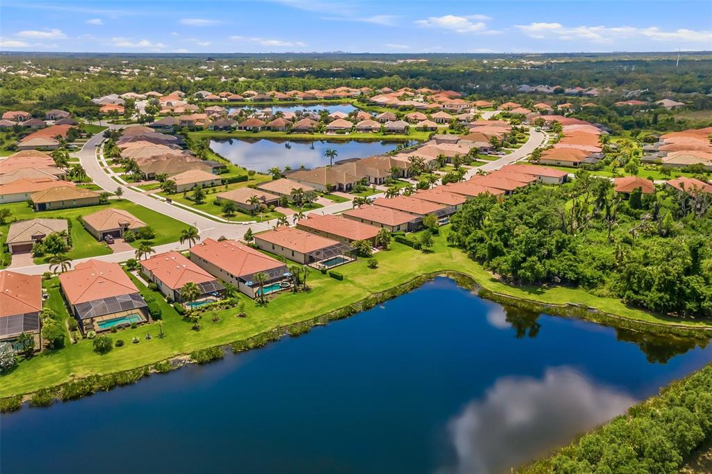 An aerial view shows a suburban neighborhood with houses, swimming pools, and two large ponds — 10103 MARBELLA DRIVE, BRADENTON, FL