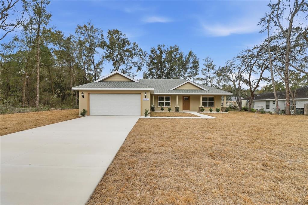 A single-story house with a tan exterior, a two-car garage, and a concrete driveway — 10244 N ATHENIA DRIVE, CITRUS SPRINGS, FL