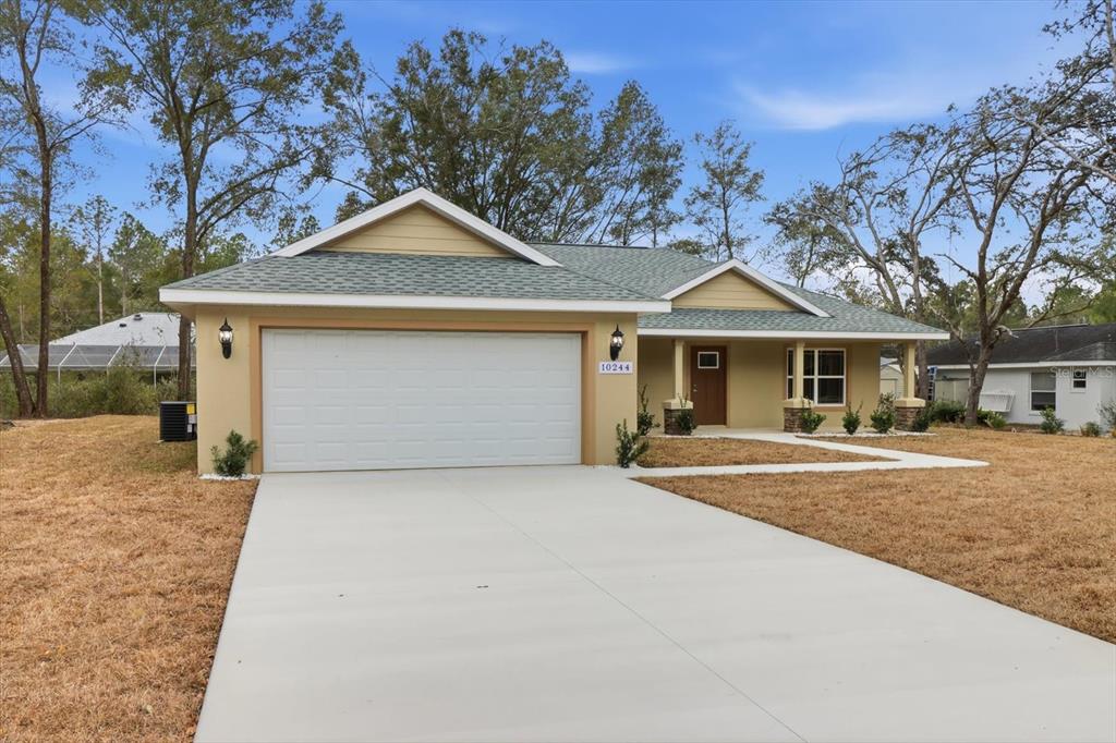 A single-story house with a tan exterior, a two-car garage, and a concrete driveway — 10244 N ATHENIA DRIVE, CITRUS SPRINGS, FL
