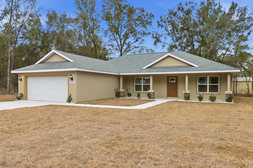 A single-story house with a tan exterior, green roof, and attached two-car garage — 10244 N ATHENIA DRIVE, CITRUS SPRINGS, FL