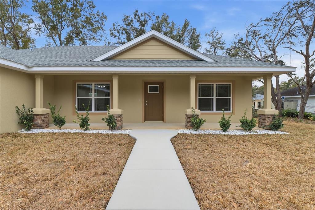 A single-story house with a tan exterior, a covered front porch, and a concrete walkway — 10244 N ATHENIA DRIVE, CITRUS SPRINGS, FL
