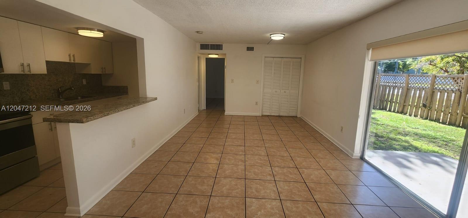 An open-concept living and dining area features tile flooring, a kitchen pass-through, and sliding doors — 4134 NW 79th Ave # 1C, Doral FL 33166, DORAL, FL