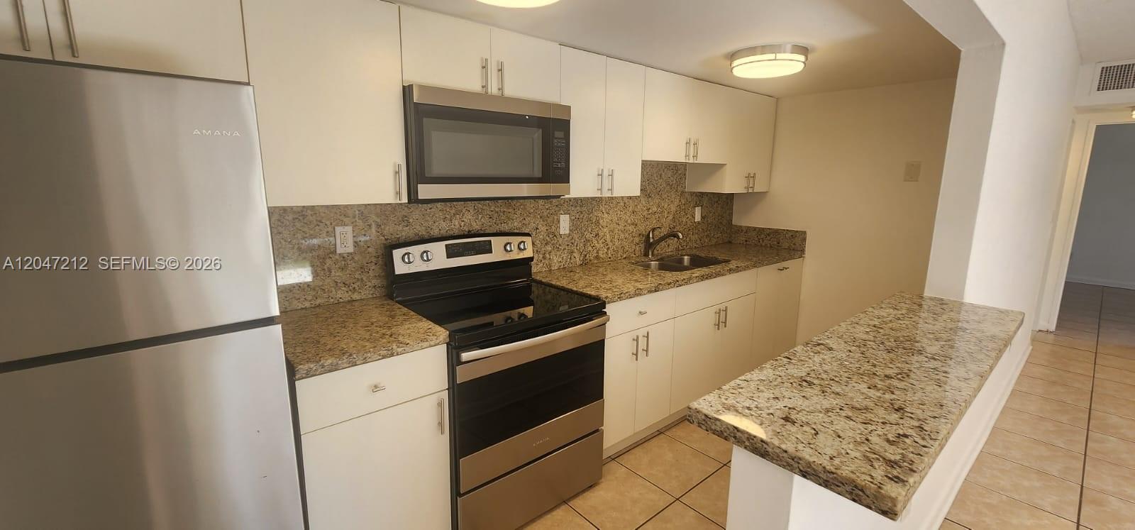 A kitchen features white cabinets, granite countertops, and stainless steel appliances — 4134 NW 79th Ave # 1C, Doral FL 33166, DORAL, FL