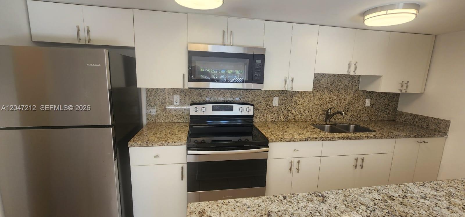 A kitchen features white cabinets, granite countertops, and stainless steel appliances — 4134 NW 79th Ave # 1C, Doral FL 33166, DORAL, FL