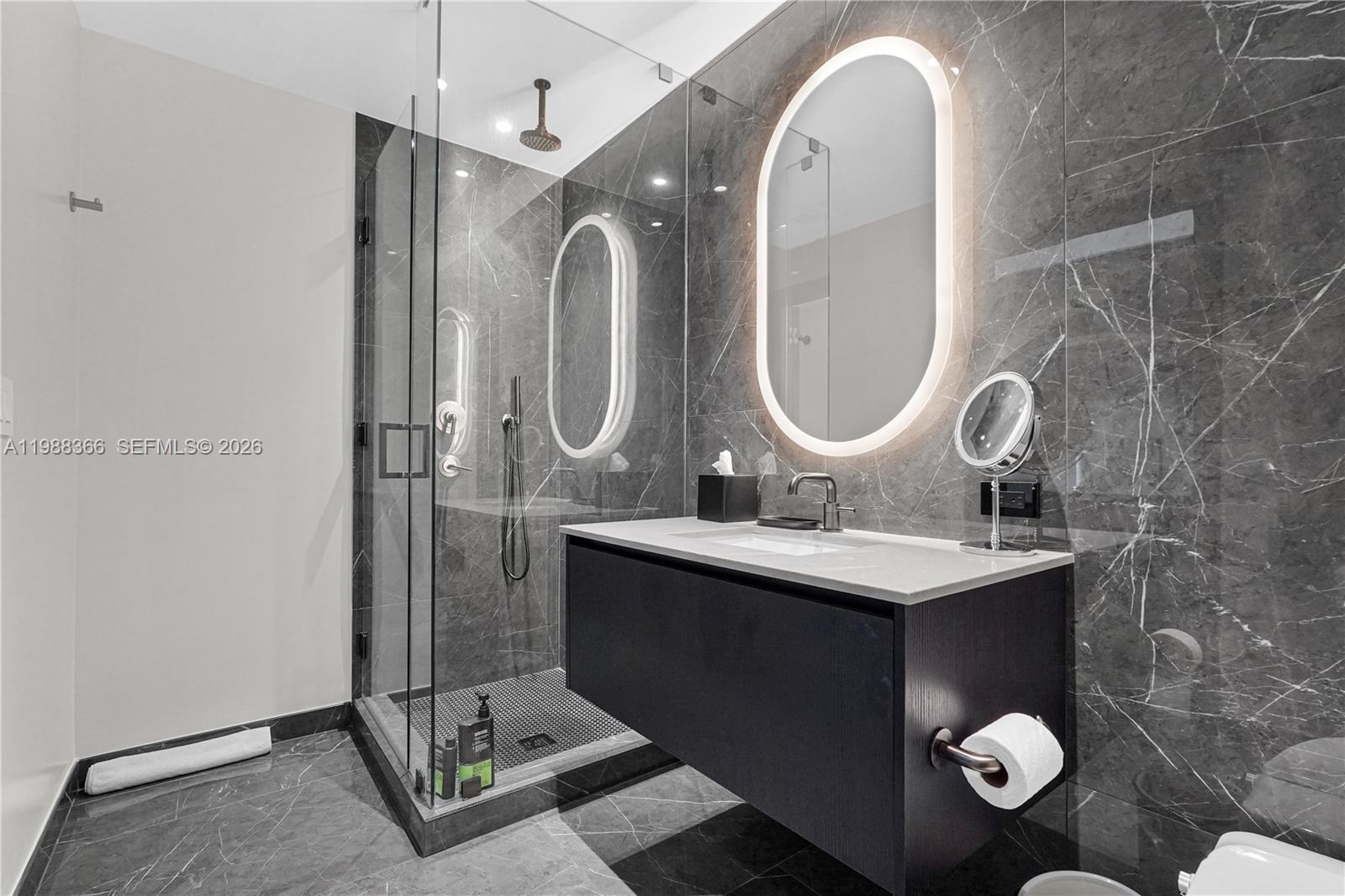 A modern bathroom features a floating vanity, a glass-enclosed shower, and dark marble tiling — 20 NE 11th St # 3603A, Miami FL 33132, MIAMI, FL