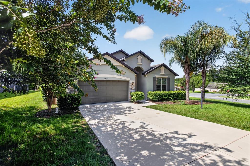 A single-story house with a two-car garage, stone accents, and a concrete driveway — 24414 WOODHILL COURT, SORRENTO, FL