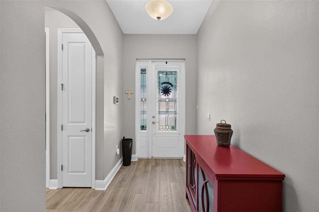 An entryway features light gray walls, wood-look flooring, a red cabinet, and a glass-paneled door — 24414 WOODHILL COURT, SORRENTO, FL