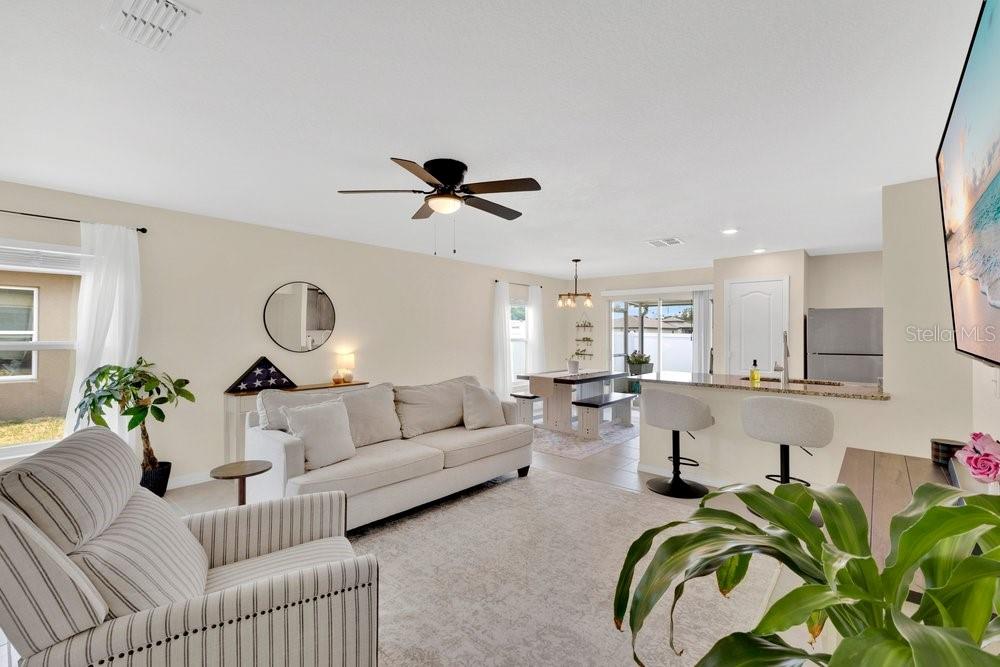 An open-concept living room and kitchen featuring a sofa, dining area, and breakfast bar — 392 KENSINGTON VIEW DRIVE, WINTER HAVEN, FL