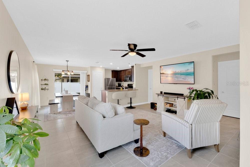 An open-concept living room and kitchen featuring tile flooring, a ceiling fan, and neutral walls — 392 KENSINGTON VIEW DRIVE, WINTER HAVEN, FL