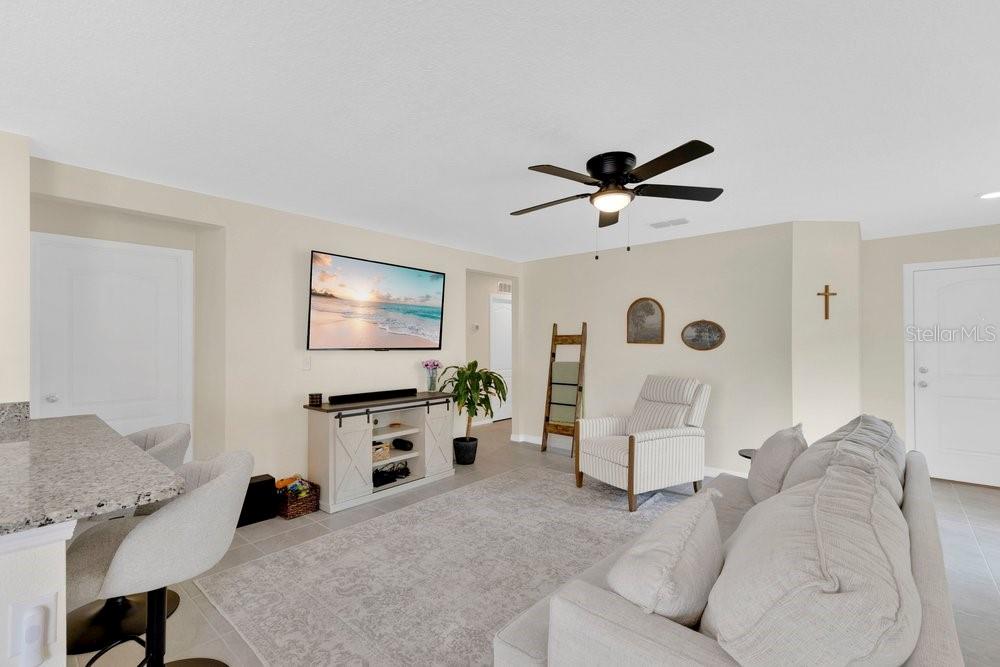A living room features a light-colored sofa, a television, and a ceiling fan — 392 KENSINGTON VIEW DRIVE, WINTER HAVEN, FL