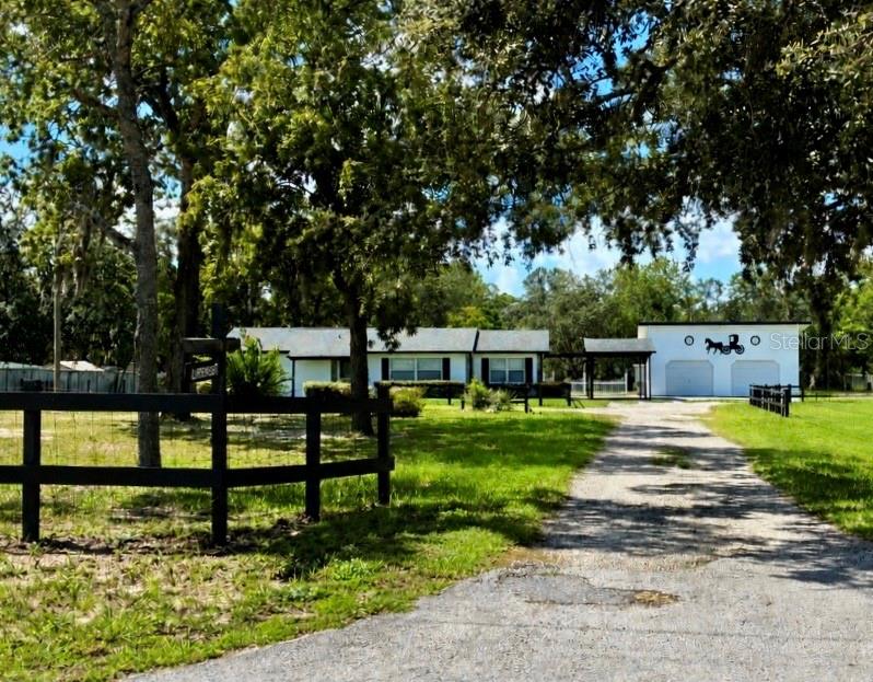 A single-story house with a detached garage sits on a grassy lot with trees — 17620 CHORVAT AVENUE, SPRING HILL, FL