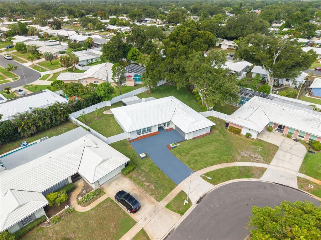 An aerial view shows a single-story house with a white roof and a blue driveway — 2065 ENVOY COURT, CLEARWATER, FL