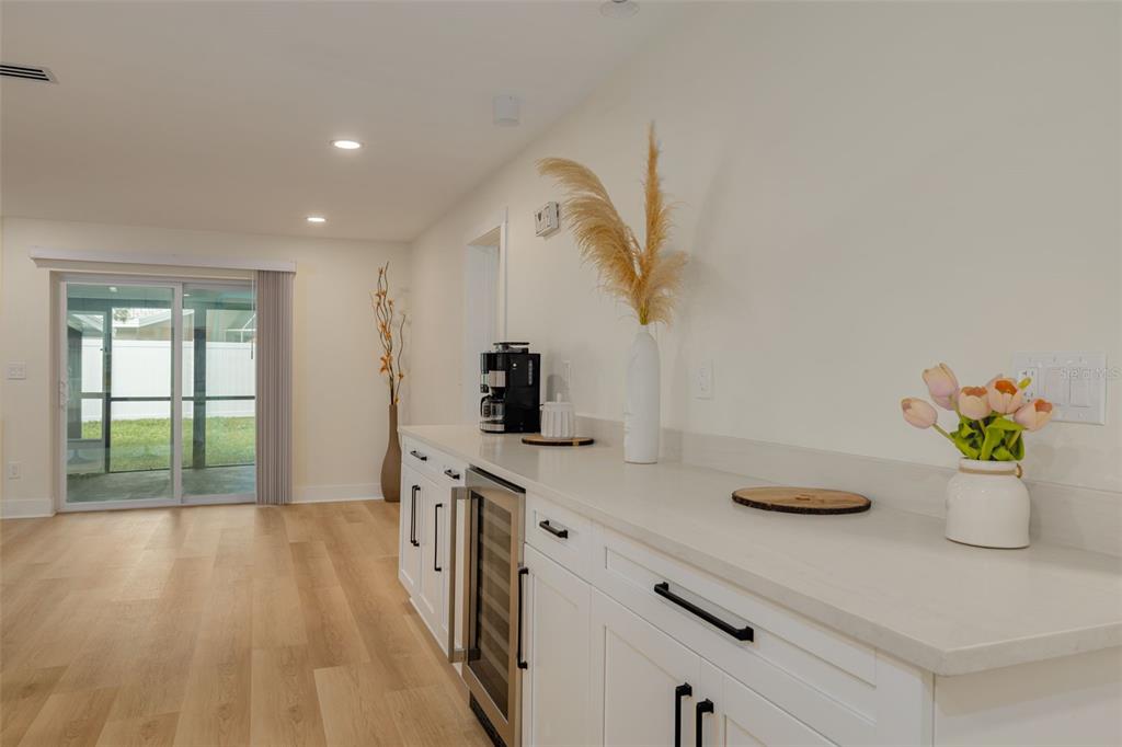 A white kitchen counter with a wine cooler, coffee maker, and decor sits near a sliding door — 2065 ENVOY COURT, CLEARWATER, FL