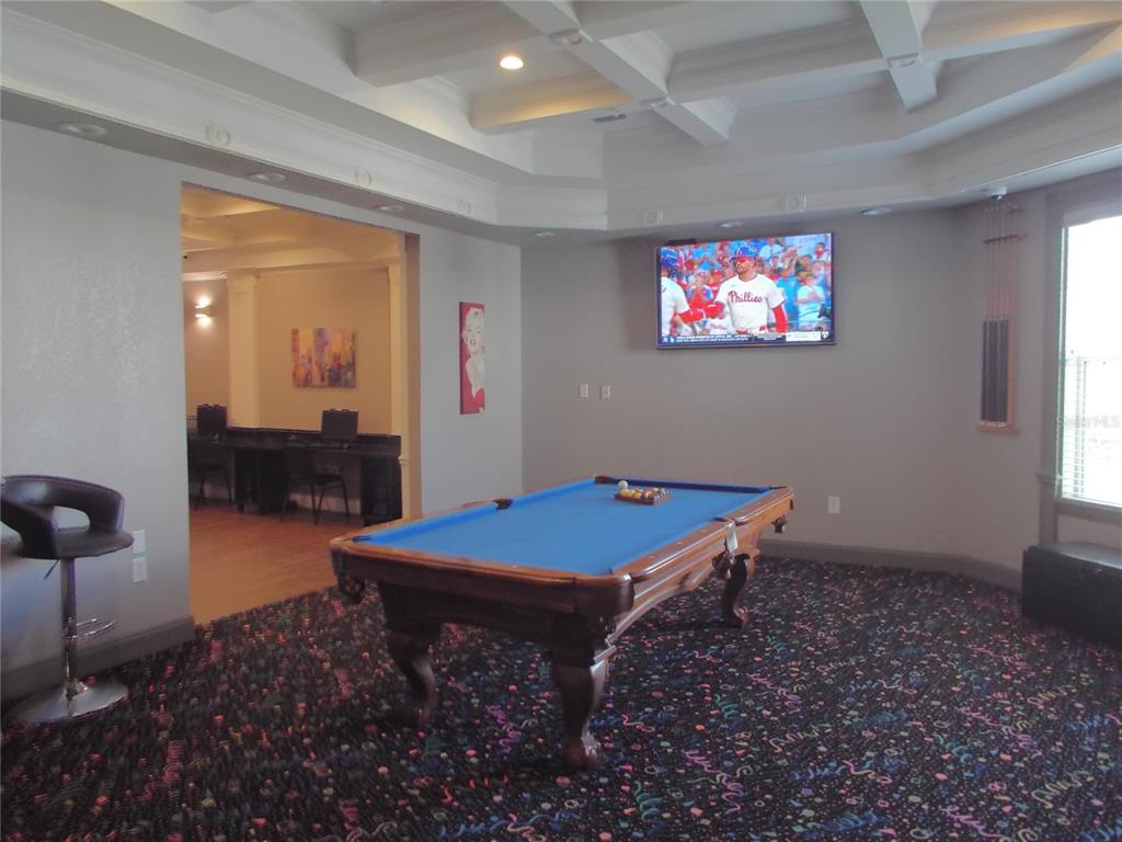A game room features a blue pool table, patterned carpet, and a wall-mounted television — 304 SOUTHERN PECAN CIRCLE UNIT 208, WINTER GARDEN, FL