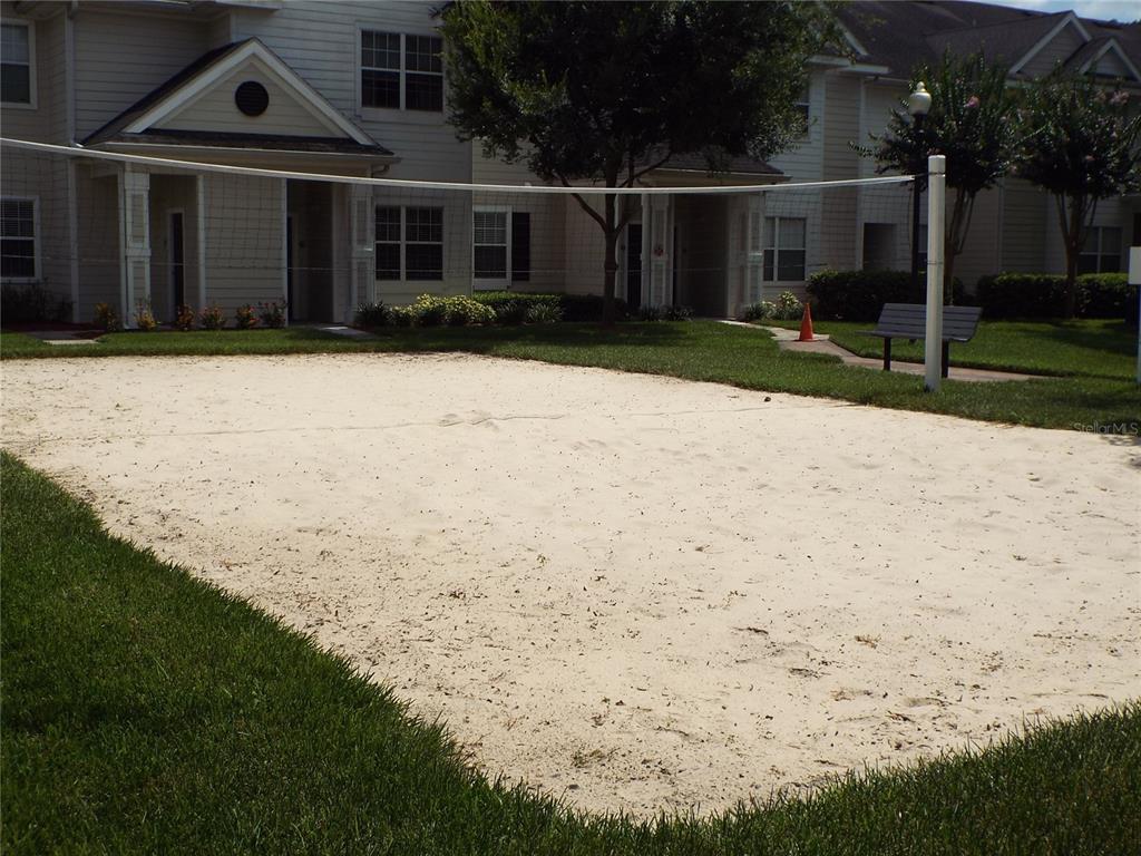 A sand volleyball court sits in front of a multi-story apartment building — 304 SOUTHERN PECAN CIRCLE UNIT 208, WINTER GARDEN, FL