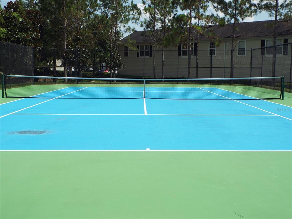 A bright blue and green tennis court is enclosed by a black chain-link fence — 304 SOUTHERN PECAN CIRCLE UNIT 208, WINTER GARDEN, FL