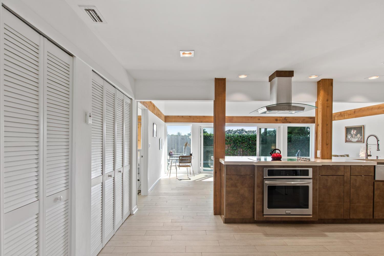 A kitchen features dark wood cabinets, a stainless steel oven, and exposed wooden support beams — 11792 Wimbledon Circle, Wellington FL 33414, WELLINGTON, FL
