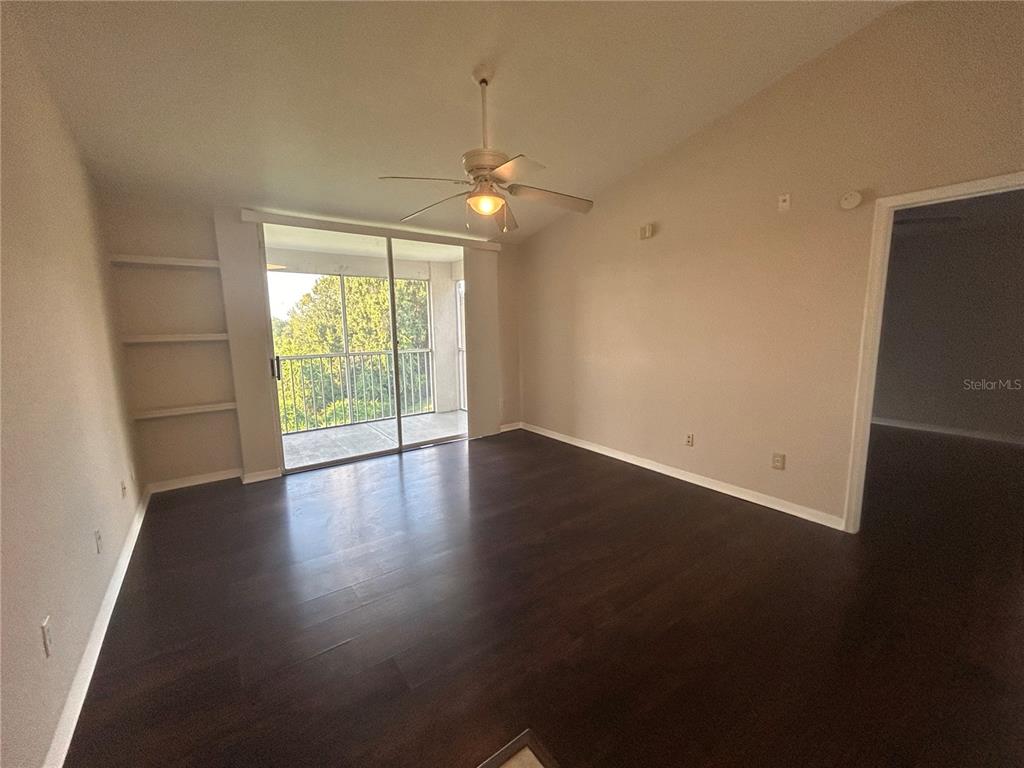 An empty room features dark wood flooring, a ceiling fan, built-in shelves, and a sliding door — 8939 LATREC AVENUE UNIT 1312, ORLANDO, FL