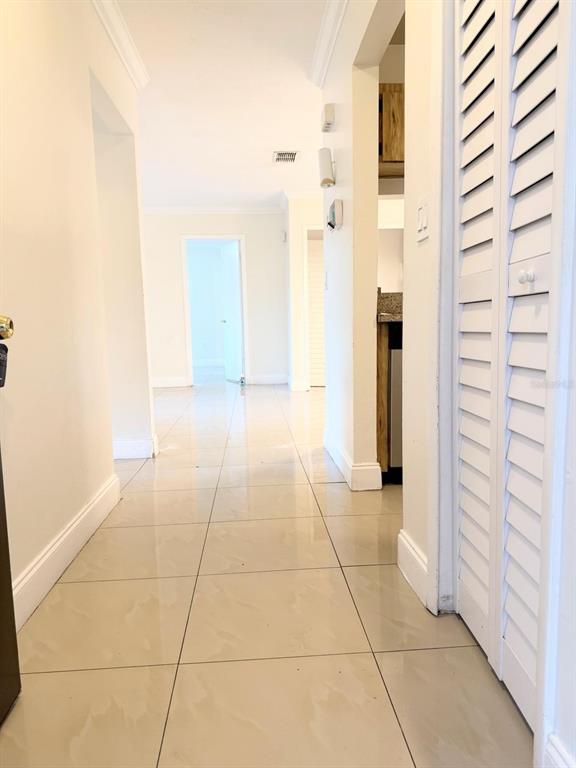 A hallway with light-colored tile flooring leads toward a doorway in the distance — 5226 VIA HACIENDA CIRCLE UNIT A215, ORLANDO, FL