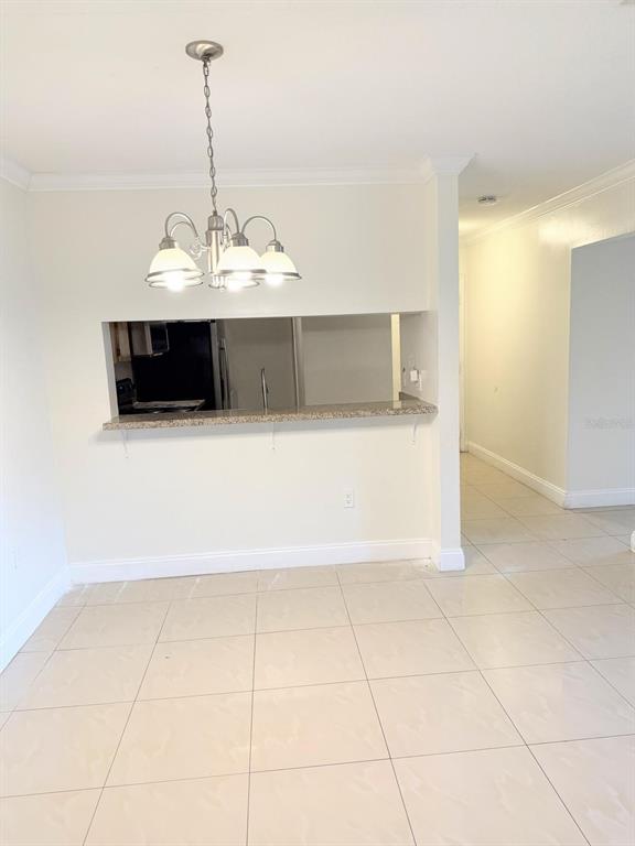 A dining area features a chandelier, a granite breakfast bar, and light-colored tile flooring — 5226 VIA HACIENDA CIRCLE UNIT A215, ORLANDO, FL