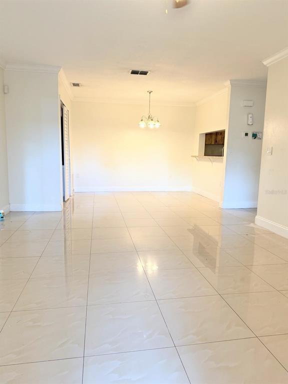 A bright, open-concept living and dining area features light-colored tile flooring and a chandelier — 5226 VIA HACIENDA CIRCLE UNIT A215, ORLANDO, FL