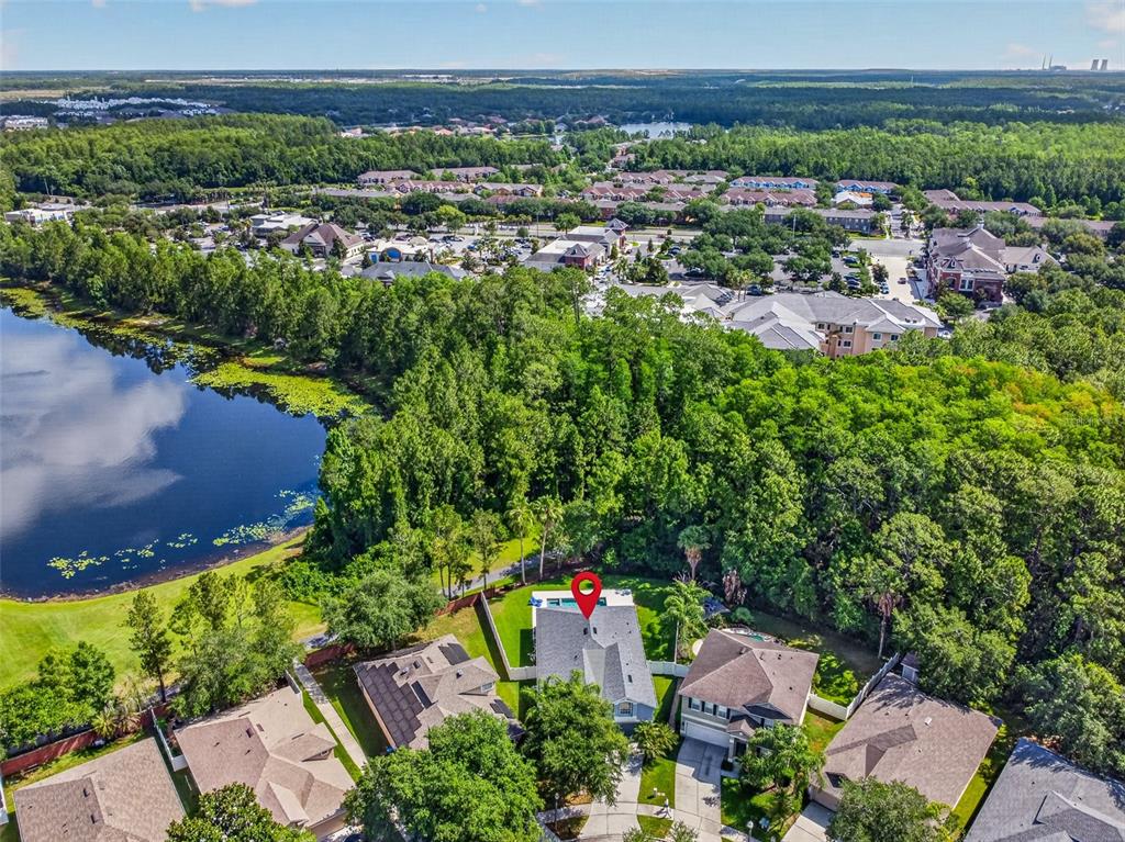 An aerial view shows a suburban house with a pool near a lake and trees — 9669 LELAND DRIVE, ORLANDO, FL