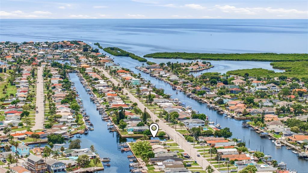 An aerial view shows a residential neighborhood with houses lining canals leading to the ocean — 4320 FLORAMAR TERRACE, NEW PORT RICHEY, FL