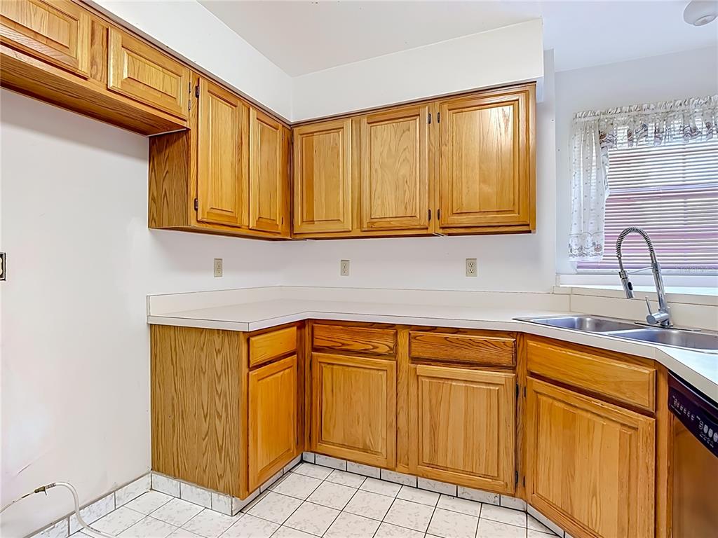 A kitchen features oak cabinets, white laminate countertops, and white tile flooring — 4130 BERGAMONT COURT, KISSIMMEE, FL