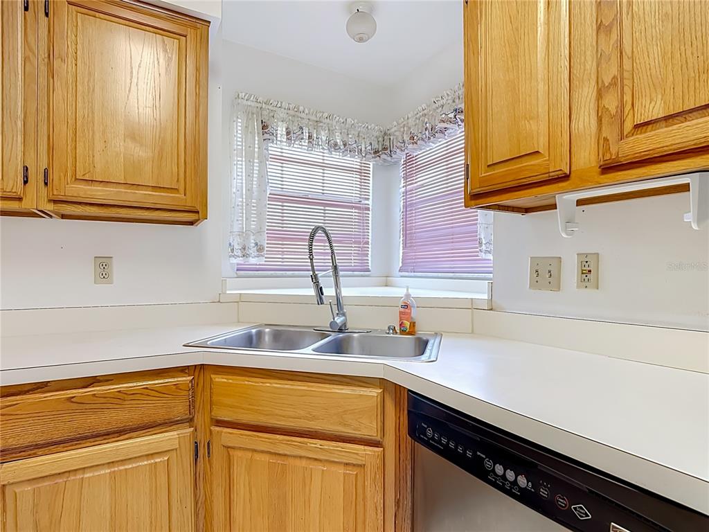 A kitchen corner features oak cabinets, a double-basin sink, and a window with blinds — 4130 BERGAMONT COURT, KISSIMMEE, FL
