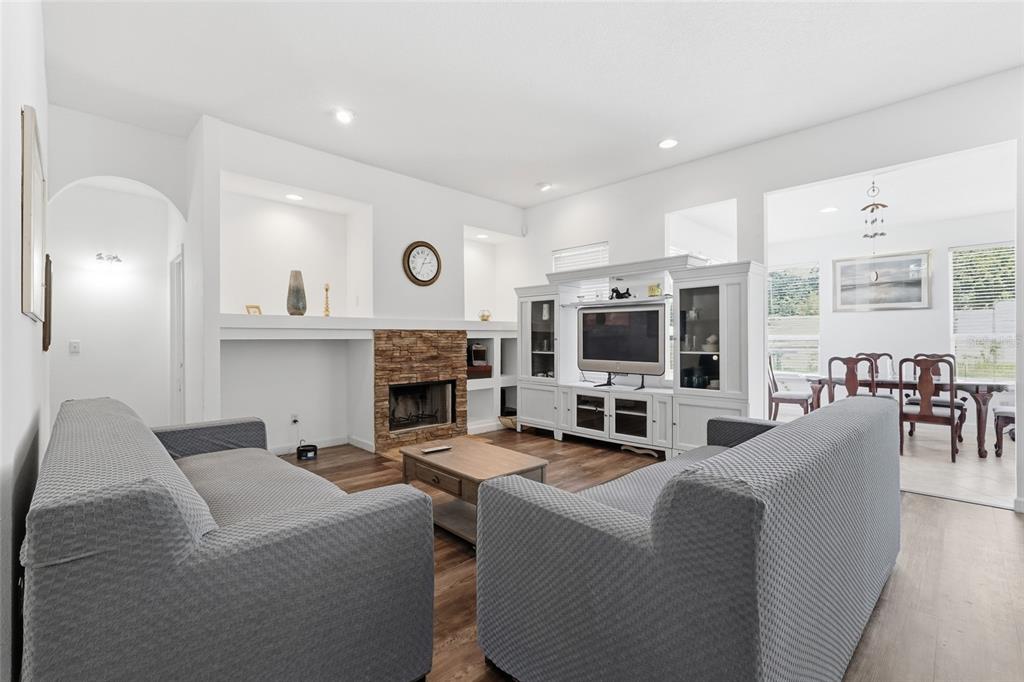 A living room features a stone fireplace, built-in shelving, gray sofas, and wood-look flooring — 9137 DOLLANGER COURT, ORLANDO, FL