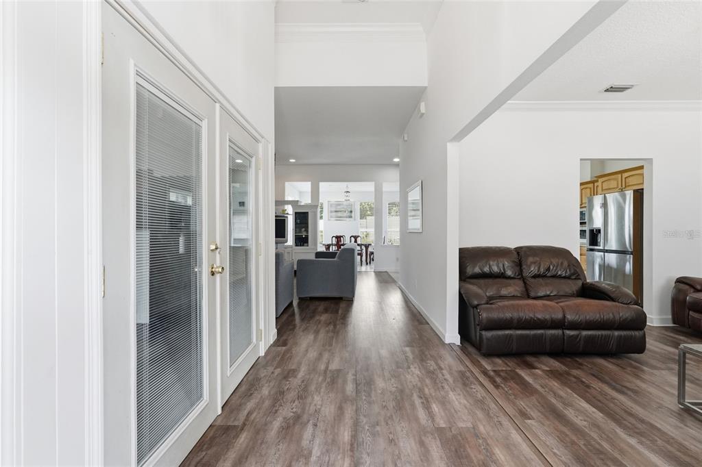 A view from a hallway looking toward a living area with wood-look flooring — 9137 DOLLANGER COURT, ORLANDO, FL