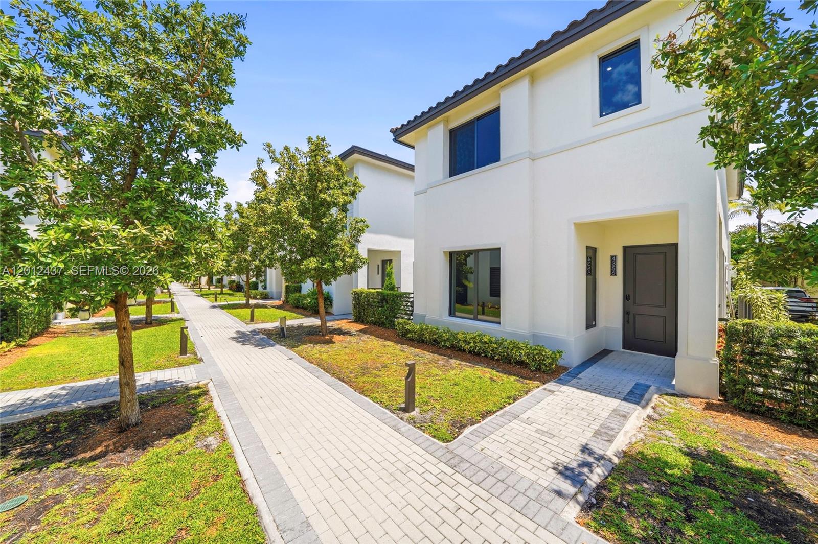 A row of modern two-story white townhouses features paved walkways and landscaped front yards — 4356 NW 80th Ave, Doral FL 33166, DORAL, FL