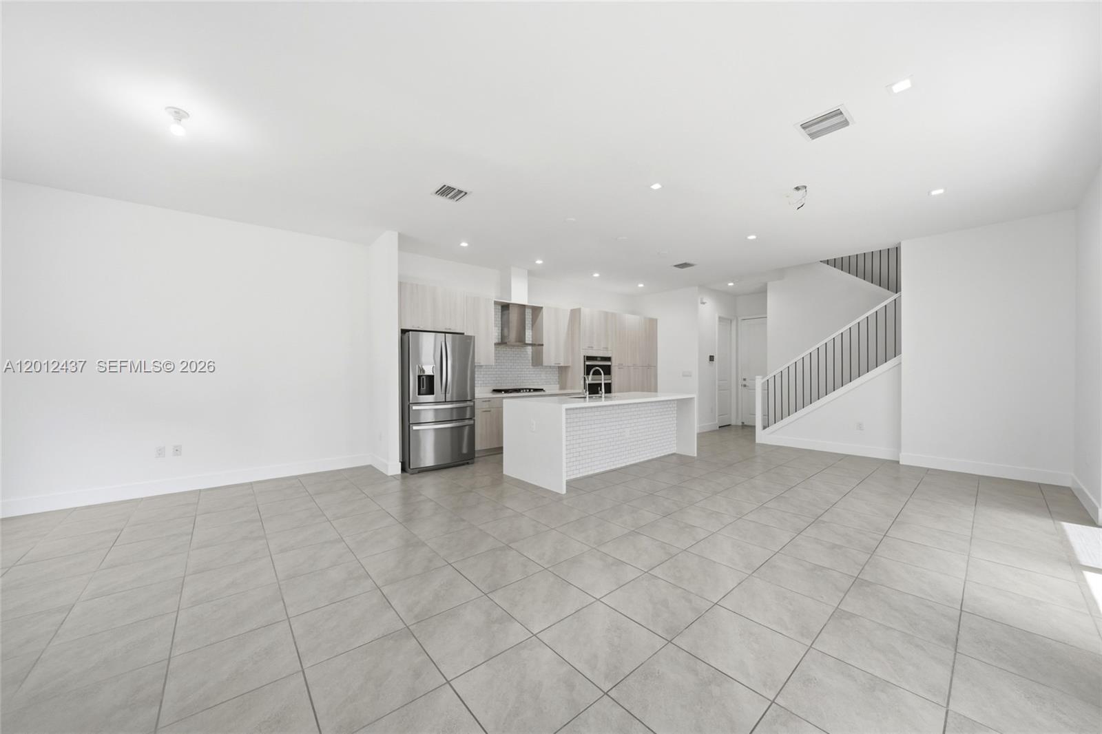 A modern open-concept kitchen and dining area features light wood cabinetry, a white island, and stairs — 4356 NW 80th Ave, Doral FL 33166, DORAL, FL