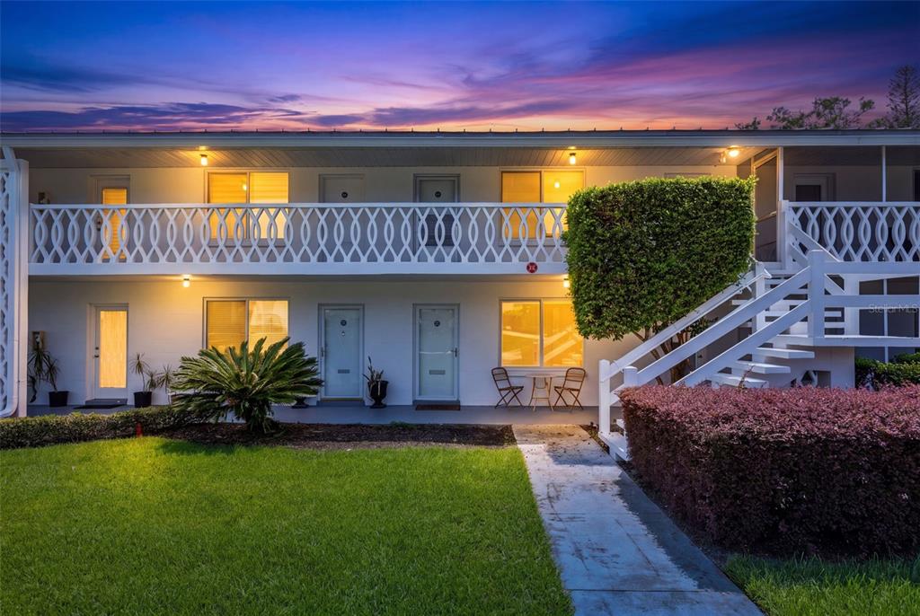 A two-story apartment building exterior features a white balcony, outdoor staircase, and landscaped lawn — 1140 S ORLANDO AVENUE UNIT B-7, MAITLAND, FL