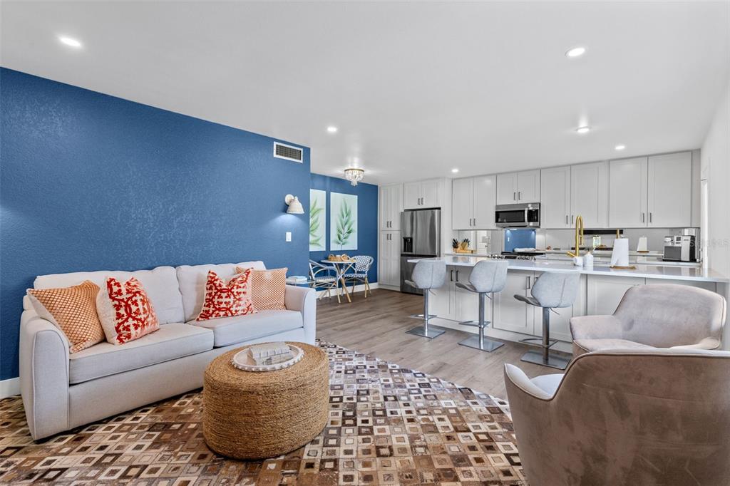 An open-concept living room and kitchen feature a blue accent wall and white cabinetry — 1140 S ORLANDO AVENUE UNIT B-7, MAITLAND, FL