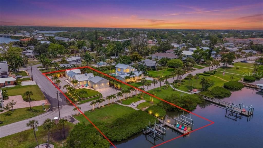 An aerial view shows a waterfront house with a private dock and landscaped yard — 216 SUNRISE DRIVE, NOKOMIS, FL