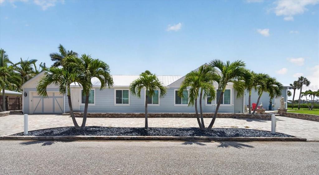 A light blue single-story house with a metal roof and palm trees in the front — 216 SUNRISE DRIVE, NOKOMIS, FL