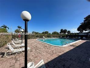 A swimming pool with lounge chairs on a paved deck under a clear blue sky — 6505 Winfield Blvd # 3, Margate FL 33063, MARGATE, FL