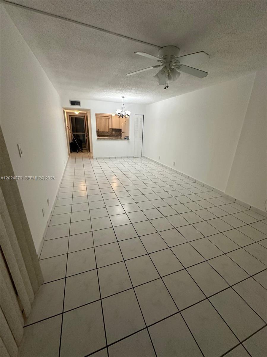 An empty living and dining area features white tile flooring, a ceiling fan, and a pass-through — 6505 Winfield Blvd # 3, Margate FL 33063, MARGATE, FL