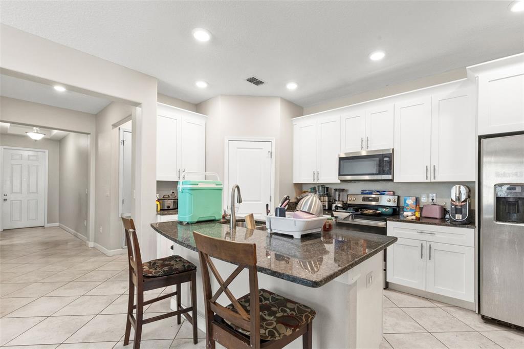 A kitchen with white cabinets, granite countertops, a center island, and stainless steel appliances — 13244 SATIN LILY DRIVE, RIVERVIEW, FL