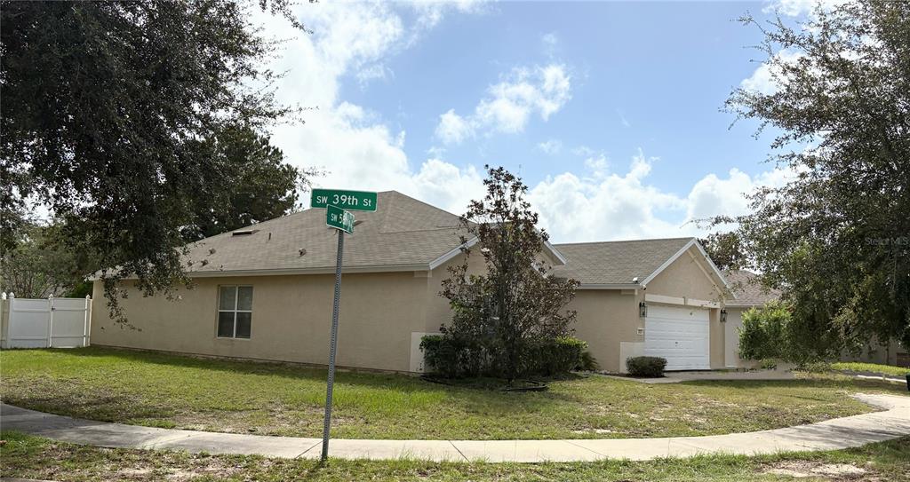 A tan, single-story suburban house with a white garage and a street sign in front — 3921 SW 58TH AVENUE, OCALA, FL