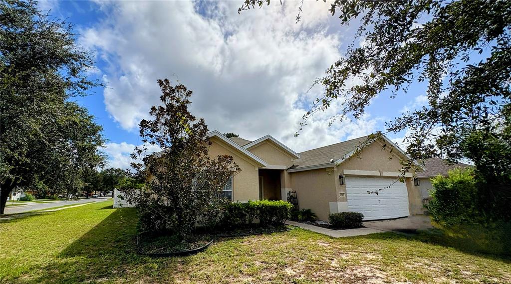 A single-story beige house with a two-car garage and a front yard with trees — 3921 SW 58TH AVENUE, OCALA, FL